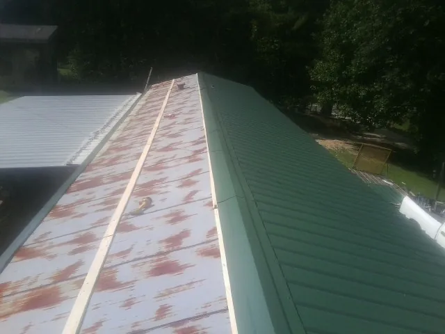 Old rusted panels beside newly installed green metal roofing — Wind Damage Roof Repair by Roofing Brothers in Rancho Mirage