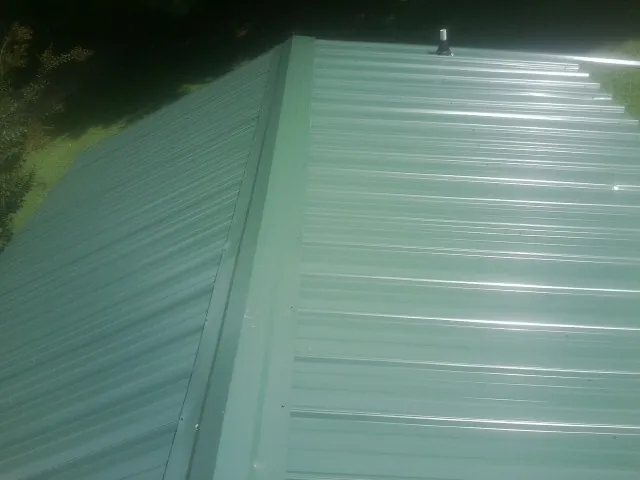 New green metal panels meeting at the ridge of a roof — Flat Roof Repair work by our crew in Rancho Mirage