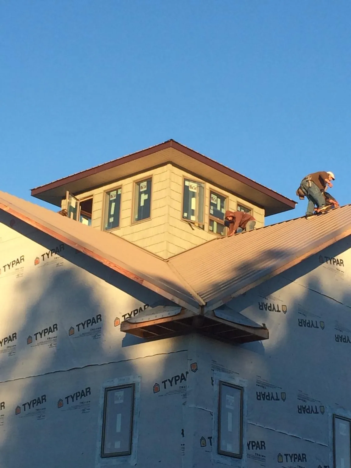 Roofers working around a rooftop cupola on a new metal roof at sunset — Roof Waterproofing in Rancho Mirage by Roofing Brothers